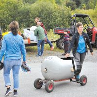 Katie Bujold voit aux bolides alors que d’autres les remontent pour la prochaine course – Photo : Michel Fortier