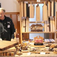 M. André Hamel, gagnant du concours Le plus bel étal 2019, devant son kiosque, expliquait avec passion le type de bois choisi pour fabriquer une place à découper ou une planche à fromage. – Photo : Yves Briand